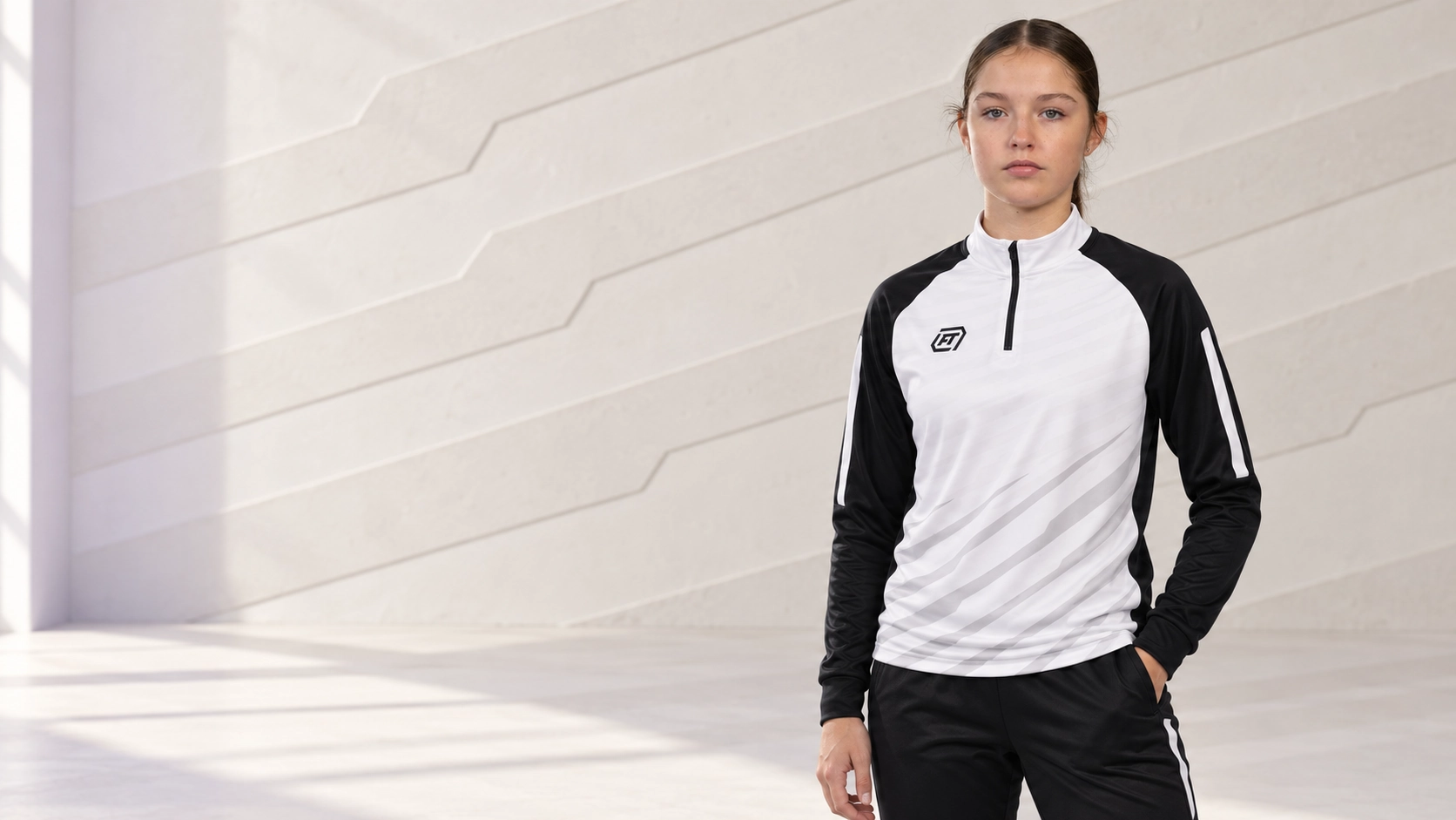 Athlete wearing a white and black FTACT quarter zip in a light training studio