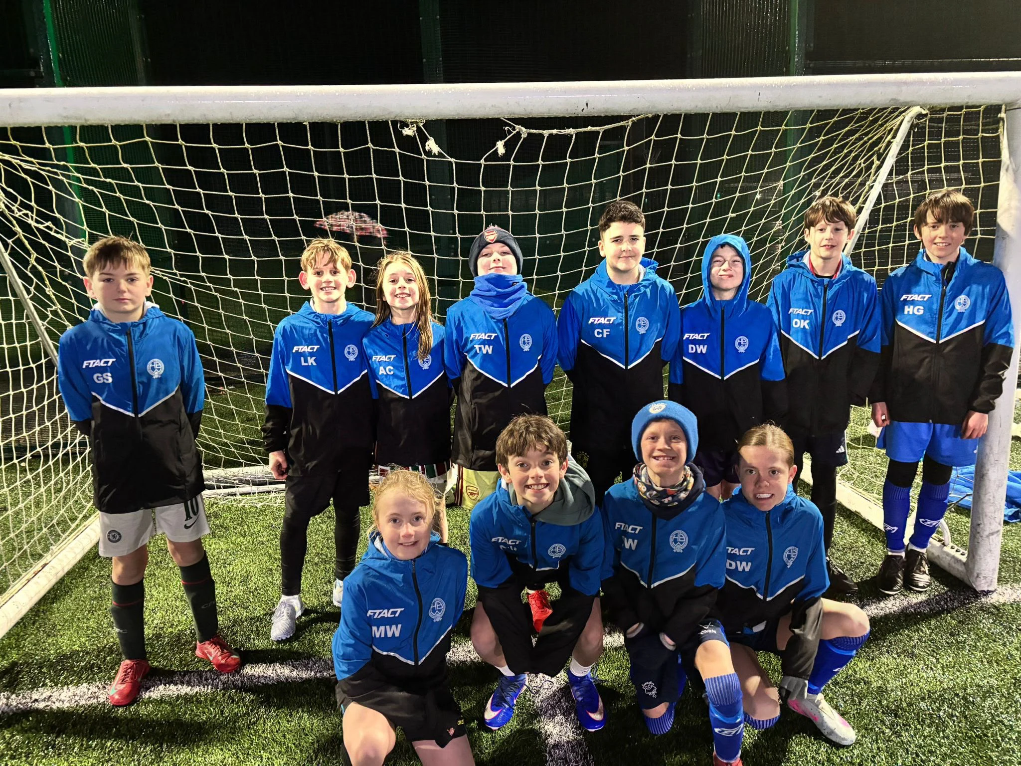 Youth team together in matching blue and black FTACT club jackets